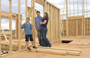 Family standing on wooden beams in a house under construction.