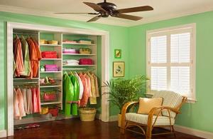 Brightly colored closet with neatly arranged clothes and a cozy chair.