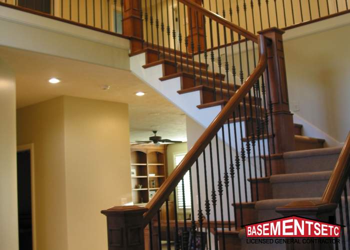 Interior view of a staircase with wooden railings and a light wall.