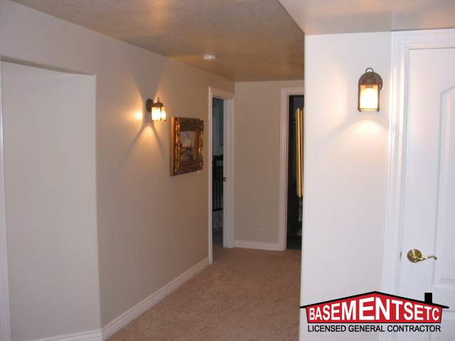 Well-lit basement hallway featuring wall sconces and a decorative frame.