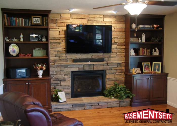 Cozy living room with stone fireplace, TV, and wooden shelves