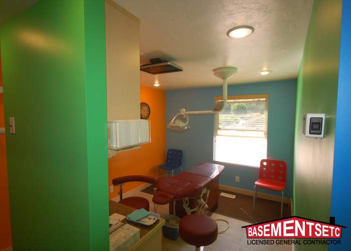 Brightly colored dental office interior with treatment chair and equipment.