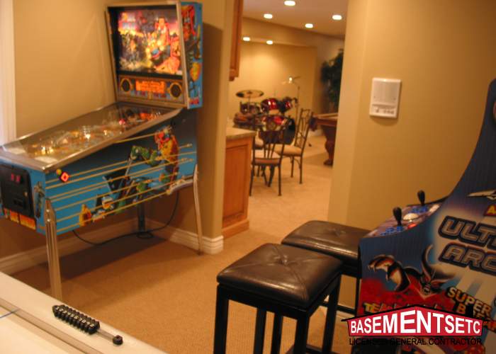 A basement playroom featuring a pinball machine and arcade game with seating.