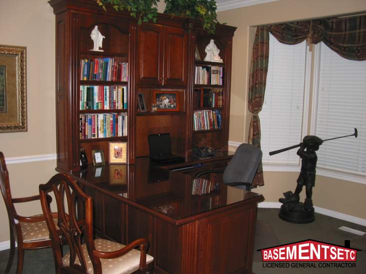 Cozy basement office with wooden desk, bookshelves, and decorative statue.