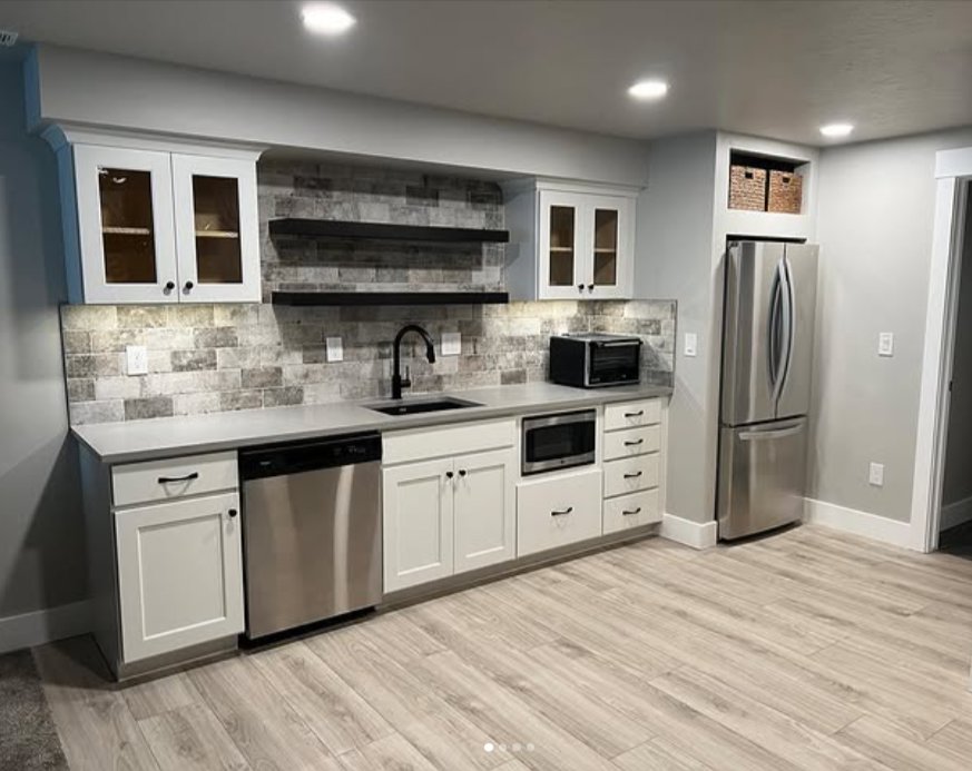Modern kitchen with white cabinets, stainless steel appliances, and gray tile backsplash.