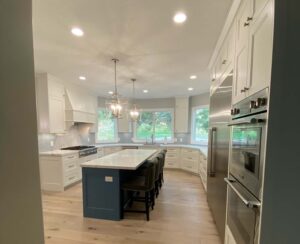 Custom kitchen remodel with blue island, white shaker cabinets, quartz countertops, and wide plank hardwood flooring.