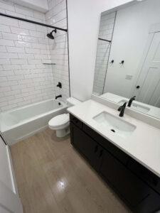 Bathroom remodel in a Herriman, Utah home featuring a white subway tile tub shower, black vanity, and modern fixtures