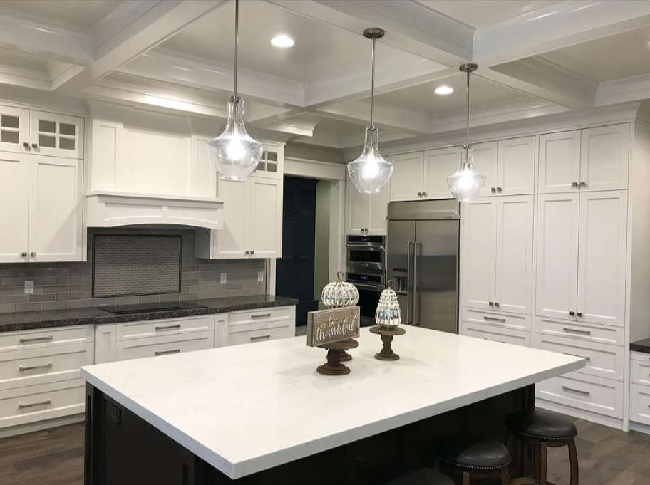 Custom kitchen remodel in Riverton Utah featuring white cabinets, large island, pendant lighting, and stainless steel appliances